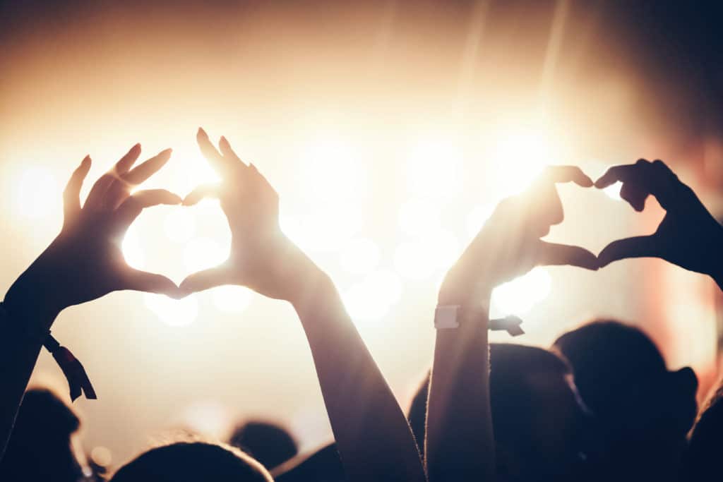 Cheering crowd with hands in air enjoying at music festival